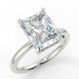 Elongated radiant cut centre stone with rounded plain band. Accent diamond gallery and non-cathedral setting