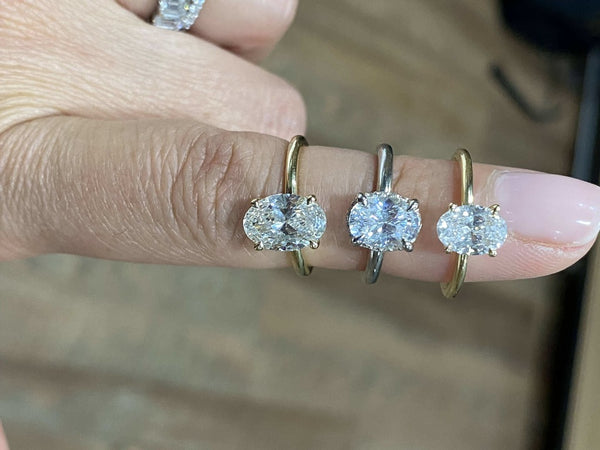 Three moissanite engagement rings stacked on a finger.